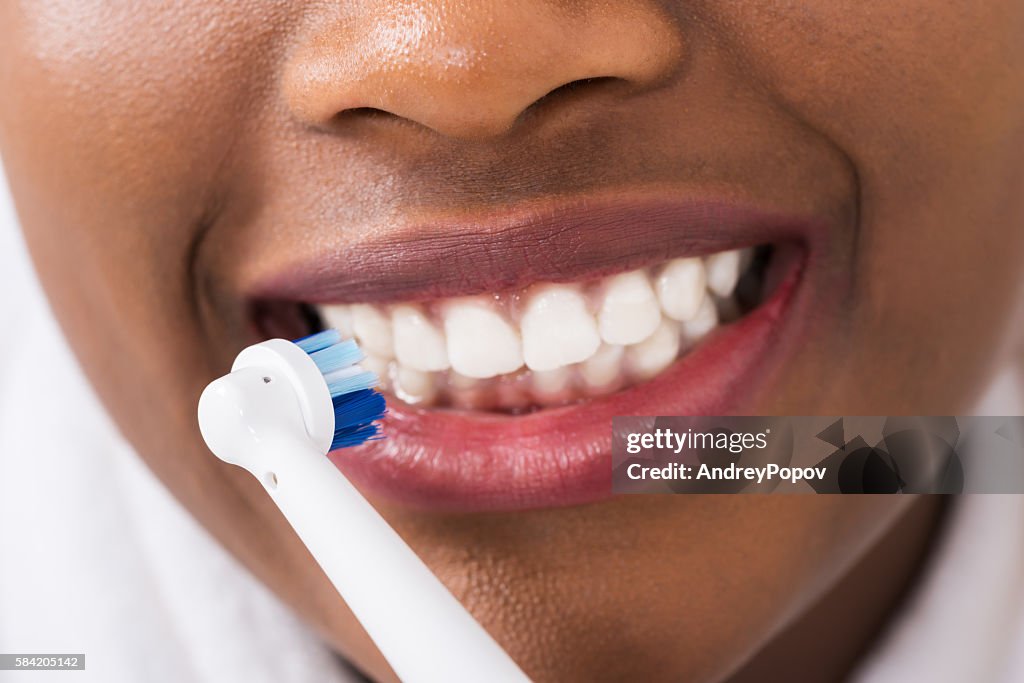 Woman Brushing Teeth With Electric Toothbrush