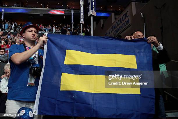 Attendees hold up a flag with the Human Rights Campaign logo during the fourth day of the Democratic National Convention at the Wells Fargo Center,...