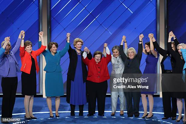 Members of the Democratic Women of the Senate raise their hands after delivering remarks on the fourth day of the Democratic National Convention at...