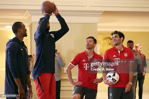 Javi Martinez and Xabi Alonso of Bayern Muenchen watch NBA players DeMarcus Cousins of Sacramento Kings and Harrison Barnes of Dallas Mavericks in an...