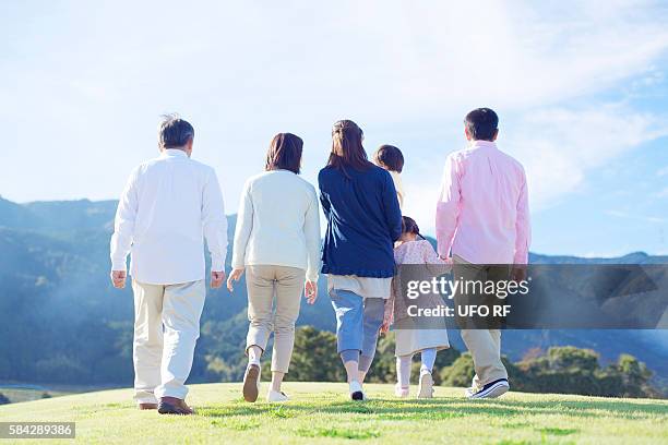 three generation family walking on hill - multi generation family from behind stock pictures, royalty-free photos & images