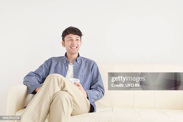 man sitting on sofa - khaki trousers stockfoto's en -beelden