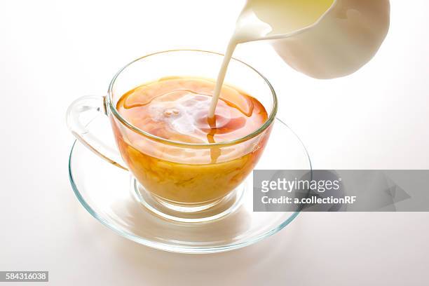 milk poured into a cup of tea - tè nero foto e immagini stock