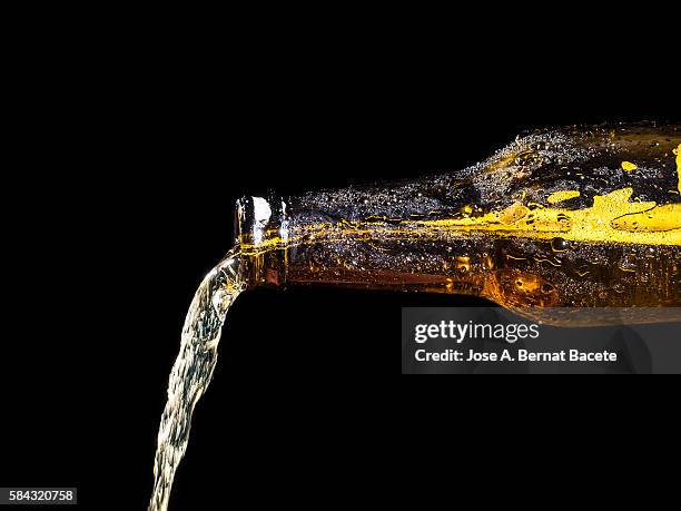 jet of a bottle of cold beer of crystal on a black bottom - beer pour stock pictures, royalty-free photos & images