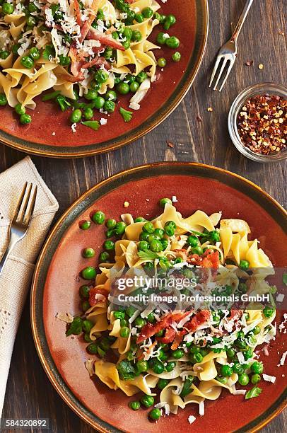 two plates of egg noodles with peas, bacon and red pepper flakes - spiral ham stock pictures, royalty-free photos & images