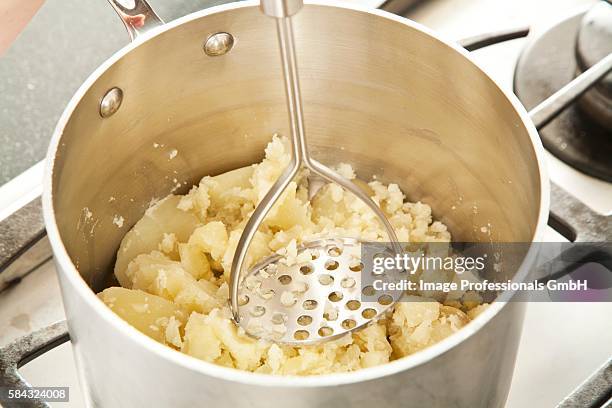 mashing potatoes in a pot - potato masher stockfoto's en -beelden
