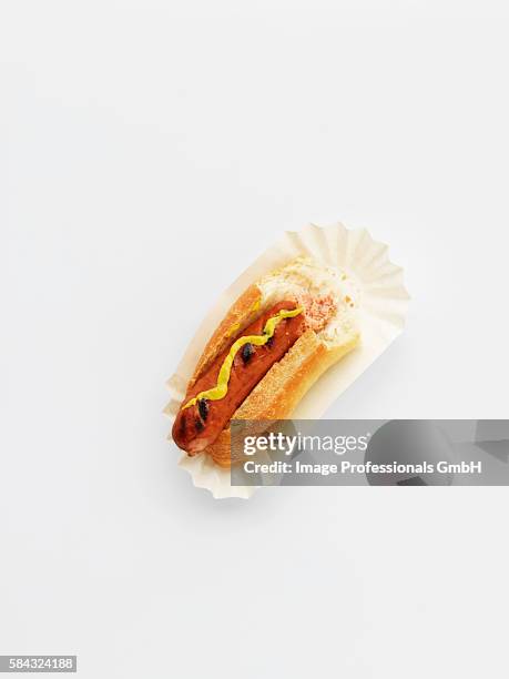 a hot dog with mustard on a paper plate with a bite taken out - eaten stock pictures, royalty-free photos & images