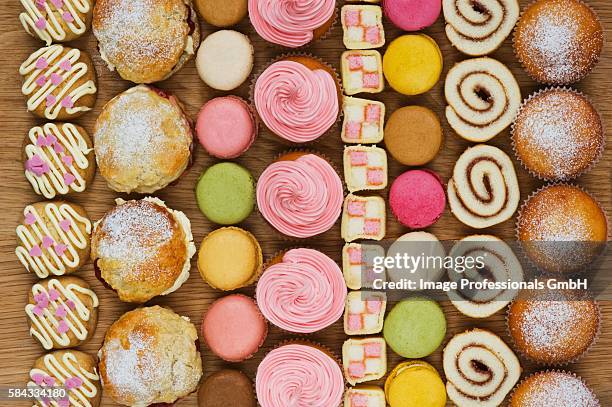 rows of cupcakes, scones, macarons, swiss rolls and pieces of mini-battenburg cake - battenburg stockfoto's en -beelden