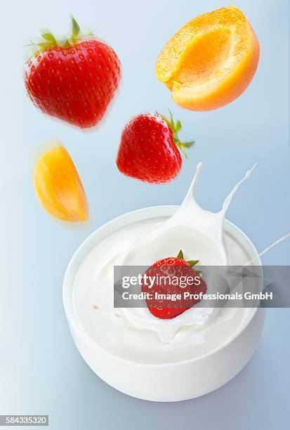 apricots and strawberries falling into yogurt - strawberry falling stock-fotos und bilder