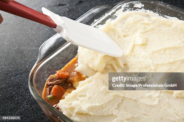 spreading mashed potato topping onto shepherds pie - mashing stock pictures, royalty-free photos & images