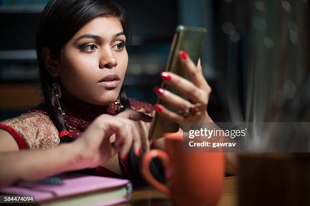 girl on study table with books coffee mug using smartphone. - coffee table reading mug stock pictures, royalty-free photos & images