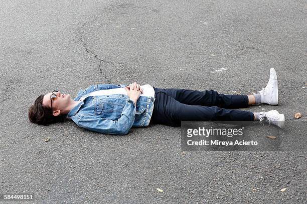 young hipster male sitting on cement ground - lying down stockfoto's en -beelden