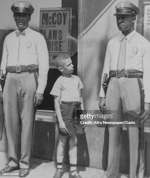 Youth Charles McGlotten looks at two African-American police officers in uniform and says that he wants to be a police officer when he grows up,...