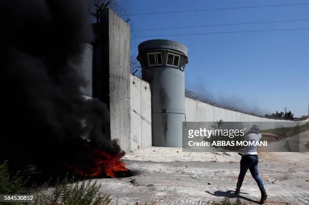 Palestinian youth throws stones towards an Israeli military post following the Friday prayer on July 29, 2016 near Qalandia, which is located next to...