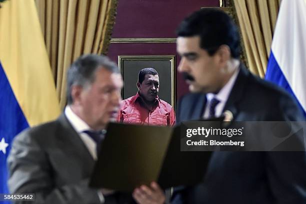 Igor Sechin, chief executive officer of Rosneft PJSC, left, holds a document while speaking with Nicolas Maduro, president of Venezuela, in front of...