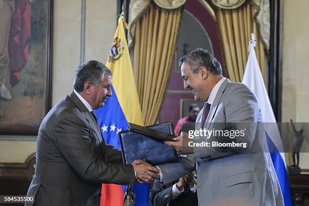 Igor Sechin, chief executive officer of Rosneft PJSC, left, and Eulogio del Pino, president of Petroleos de Venezuela SA shake hands after signing...