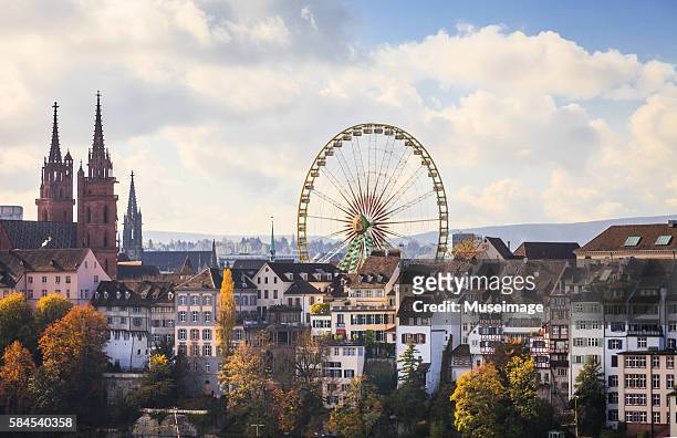 the skycape of the huge ferris wheel and basel cathedral - basel stock-fotos und bilder