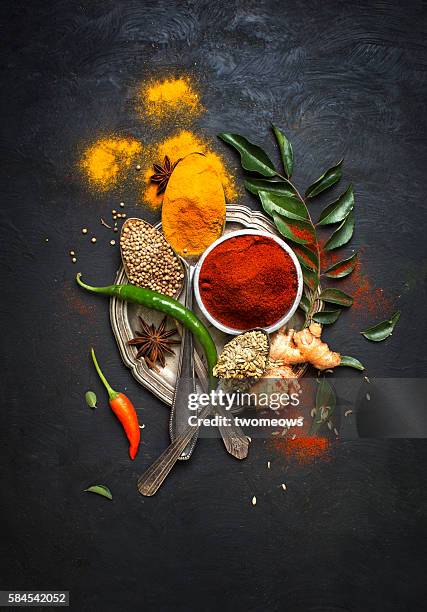 flat lay overhead view herb and spices on textured black background. - currypulver stock-fotos und bilder