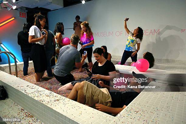 Visitors enjoy into a large pool filled with faux confetti-colored sprinkles at the Museum of Ice Cream across from the Whitney Museum on July 29,...