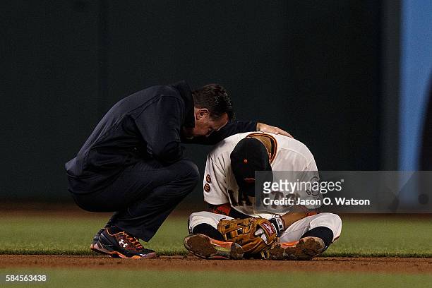 Ramiro Pena of the San Francisco Giants is examined by head athletic trainer Dave Groeschner after sustaining an injury during the seventh inning...