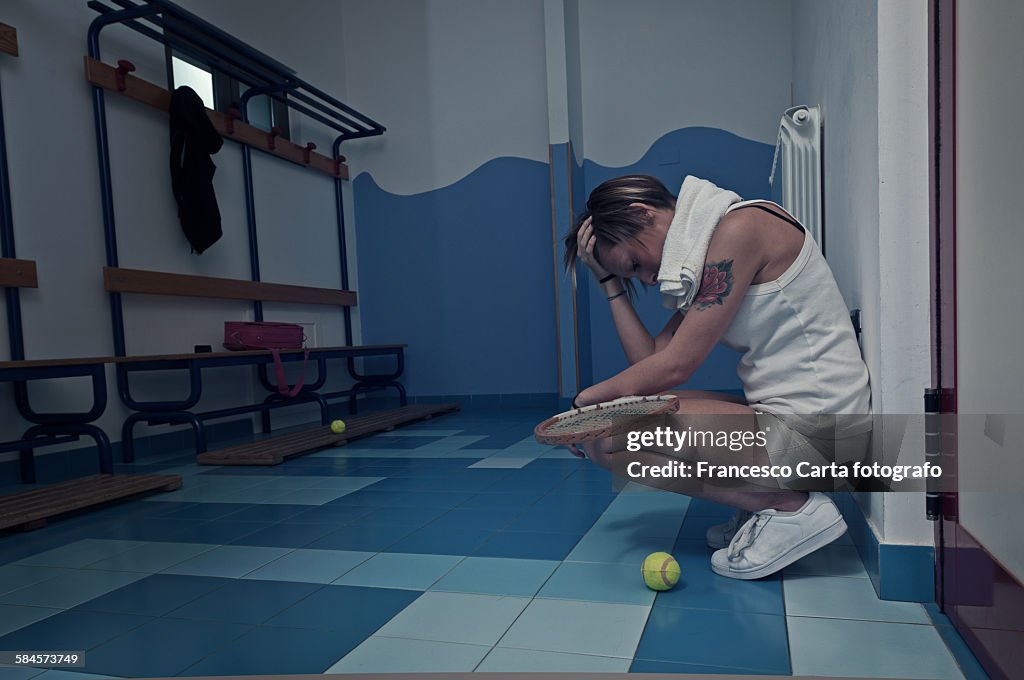 Female tennis player crouching in the locker room