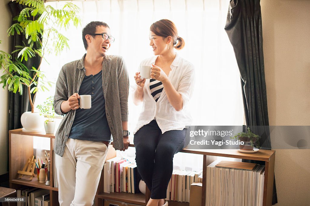 Mid adult couple drinking coffee at home