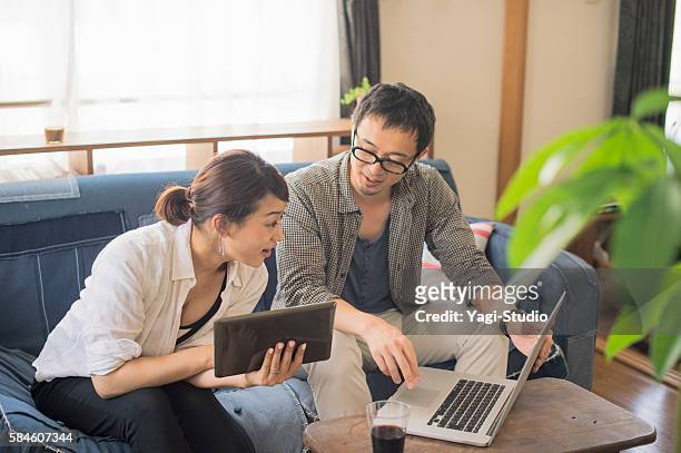 pareja adulta media usando computadora portátil y tableta digital - pareja de mediana edad fotografías e imágenes de stock