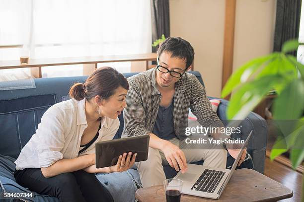 mid adult couple using laptop and digital tablet - ouder-volwassenen-koppel stockfoto's en -beelden