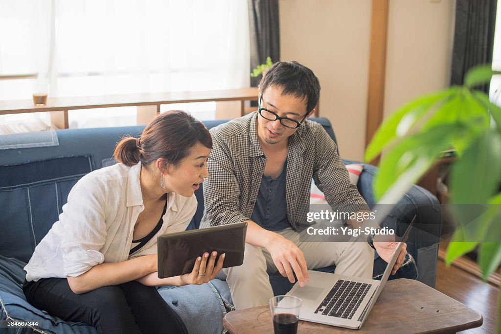 Mid adult couple using laptop and digital tablet