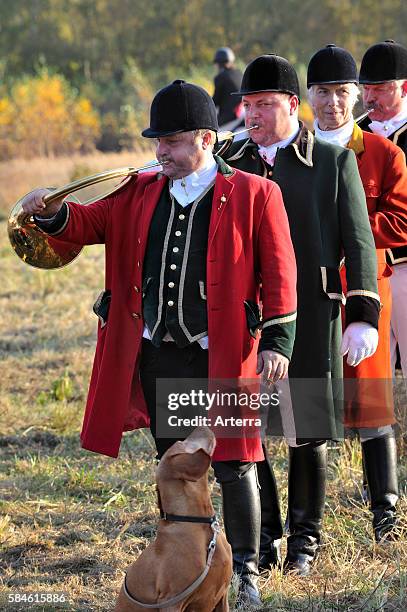 Huntsmen blowing hunting horns at drag hunting demonstration in Belgium .