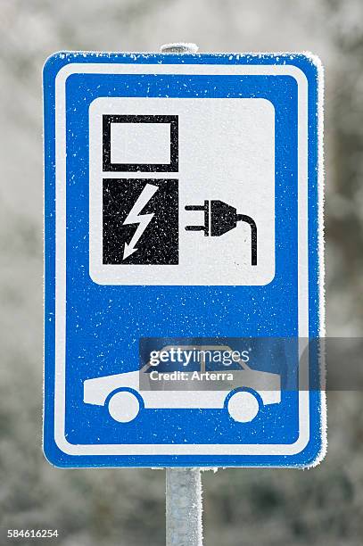 Electric car charging station sign at car park in the snow in winter, Belgium.