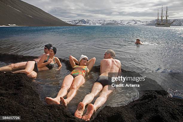 Tourists bathing in natural hot tub with volcanically heated water at Pendulum Cove, Deception Island, South Shetland Islands, Antarctica.