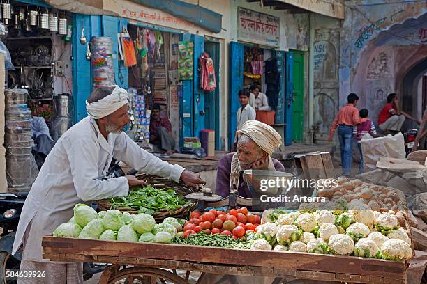 Vendors selling vegetables on wooden cart at market in Barsana / Varsana, Uttar Pradesh, India.