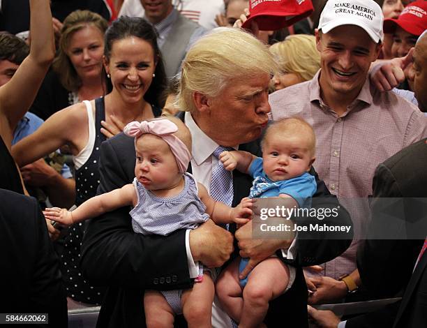 Republican presidential nominee Donald Trump kisses three-month-old Kellen Campbell, of Denver, right, and holds six-month-old Evelyn Keane, of...