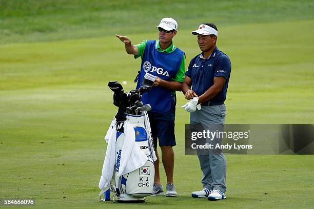 Choi of Korea and caddie Don Donatello wait on a fairway during the second round of the 2016 PGA Championship at Baltusrol Golf Club on July 29, 2016...