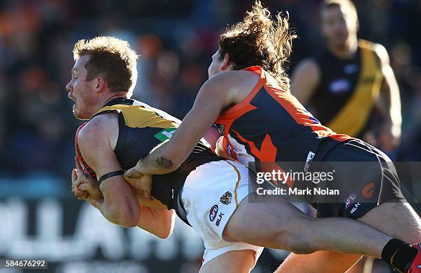 Jack Riewoldt of the Tigers takes a mark as he is tackled by Phil Davis of the Giants during the round 19 AFL match between the Greater Western...