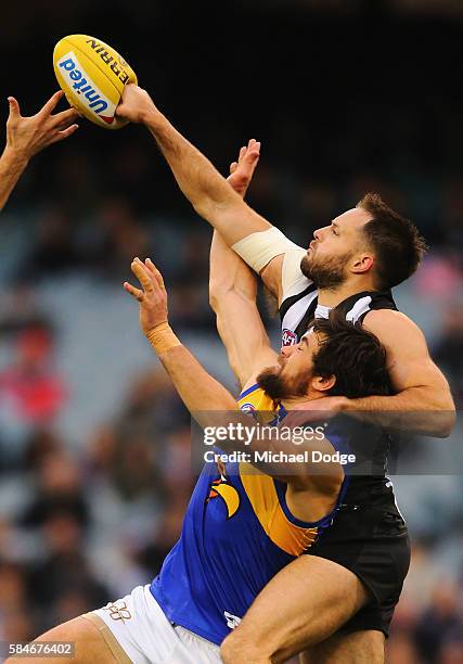 The ball compacts against the fist of Nathan Brown of the Magpies who punches away from Josh Kennedy of the Eagles during the round 19 AFL match...