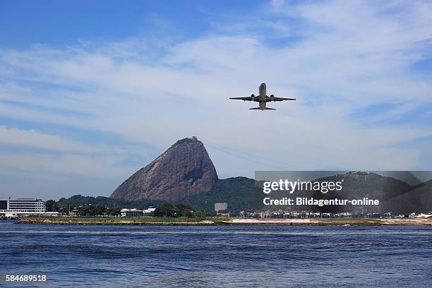 Airplane landing at the airport Aeroporto Santos Dumont, Rio de Janeiro, Brazil. In the background the Sugarloaf Mountain, Pao de Acucar.