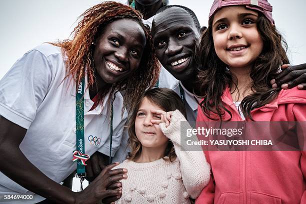 South Sudan's athlete Anjelina Nada Lohalith and James Nyang Chiengjiek for the Refugee Olympic Team take pictures with tourists in front of the...