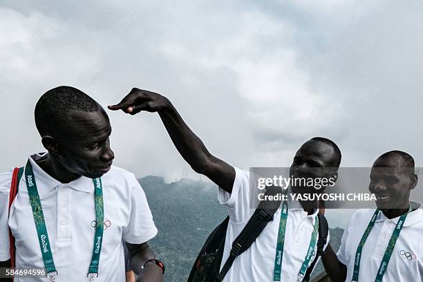 South Sudan's athlete Yiech Pur Biel and James Nyang Chiengjiek based in Kenya for the Refugee Olympic Team joke during a visit to the statue of...