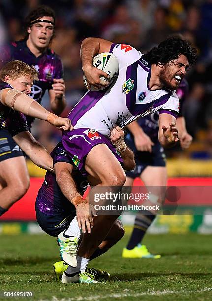 Tohu Harris of the Storm attempts to break the tackle of Ben Hannant of the Cowboys during the round 21 NRL match between the North Queensland...