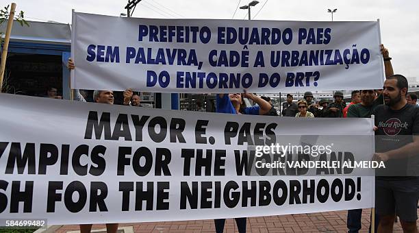 Residents of Barra de Tijuca neighbourhood hold signs to protest against the upcoming Olympic games during the inauguration of the Metro Line 4 in...