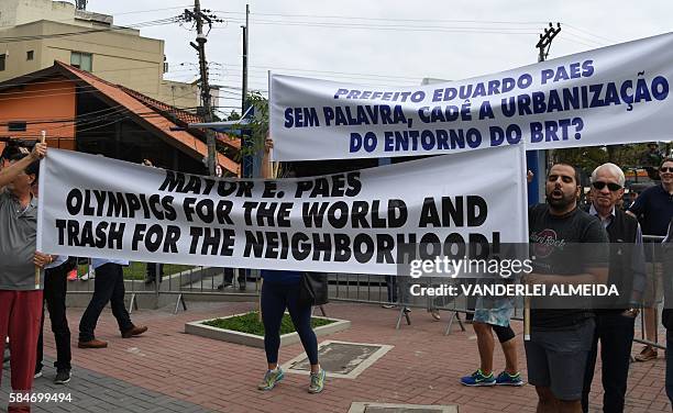 Residents of Barra de Tijuca neighbourhood hold signs to protest against the upcoming Olympic games during the inauguration of the Metro Line 4 in...