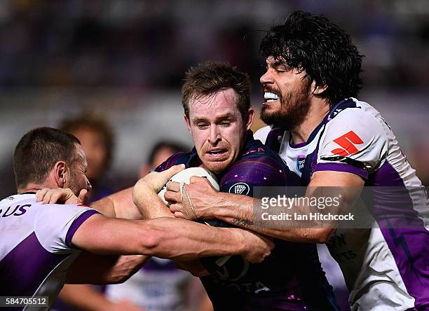 Michael Morgan of the Cowboys is tackled by Tohu Harris of the Storm during the round 21 NRL match between the North Queensland Cowboys and the...