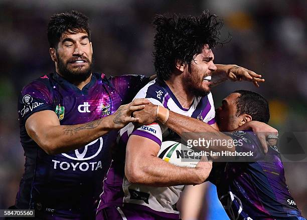 Tohu Harris of the Storm is tackled by Justin O'Neil and James Tamou of the Cowboys during the round 21 NRL match between the North Queensland...