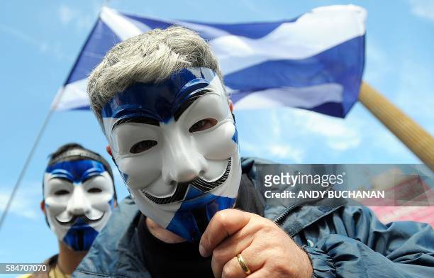 Pro-Scottish Independence supporters with Scottish Saltire flag masks pose for a picture at a rally in George Square in Glasgow, Scotland on July 30,...