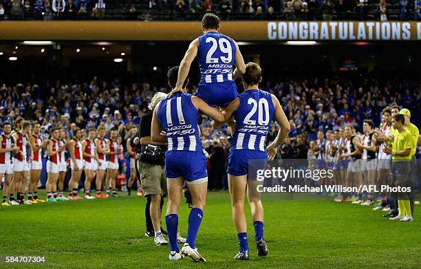 Brent Harvey of the Kangaroos is chaired from the field after his record breaking 427th match by teammates Drew Petrie and Michael Firrito during the...