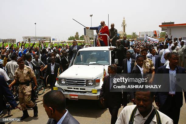 Sudanese President Omar al-Bashir greets the audience from his car as he arrives for a ceremony in his honour upon his return in the country from...