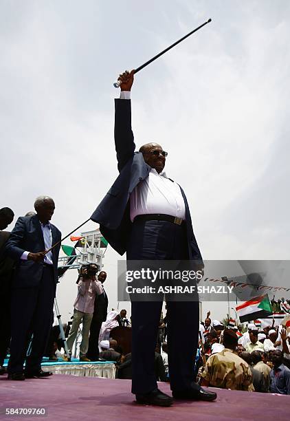 Sudanese President Omar al-Bashir greets the audience during a ceremony in his honour upon his return in the country from Ethiopia on July 30, 2016...