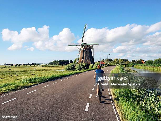 young woman in shorts riding a bike near traditional dutch windmill near maasland, holland, netherlands - dutch windmill bildbanksfoton och bilder